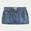 Mini-Skort aus Denim mit niedriger Leibhöhe, mittlerer Waschung und Flaggenstickerei